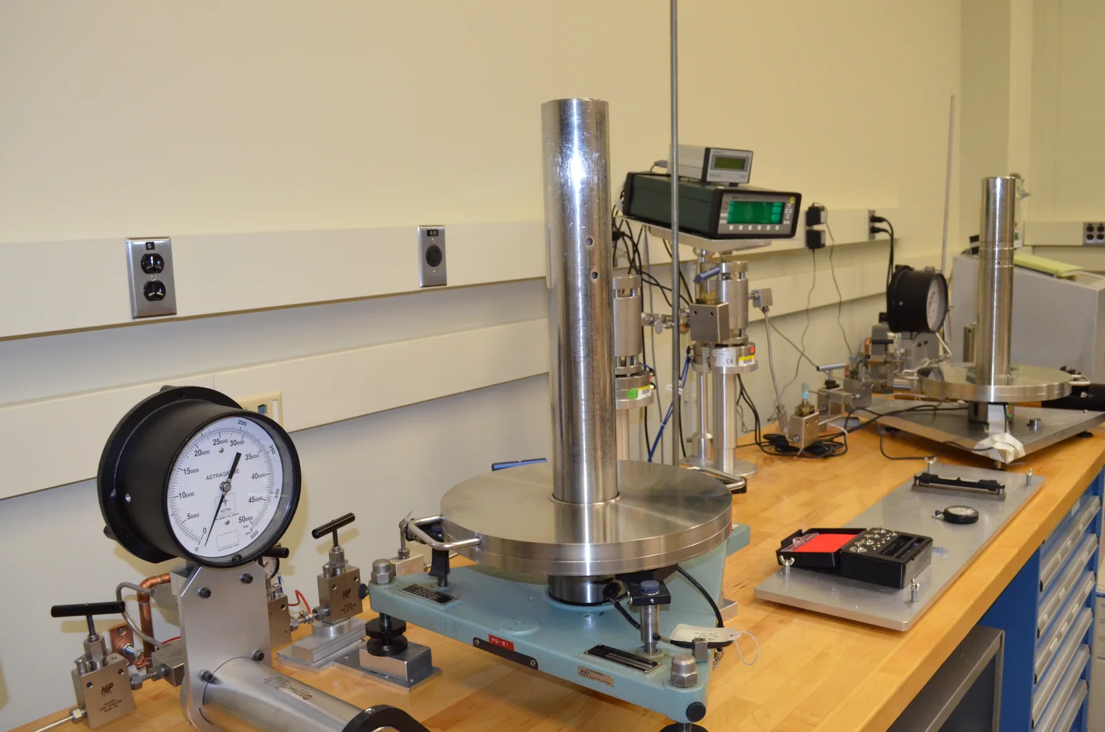 Banco de calibración de presión con manómetros y masas patrón en el NIST; imagen de referencia.
