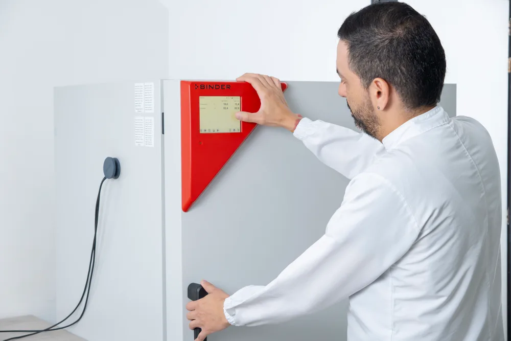 Especialista ajustando el control de una cámara térmica del laboratorio.
