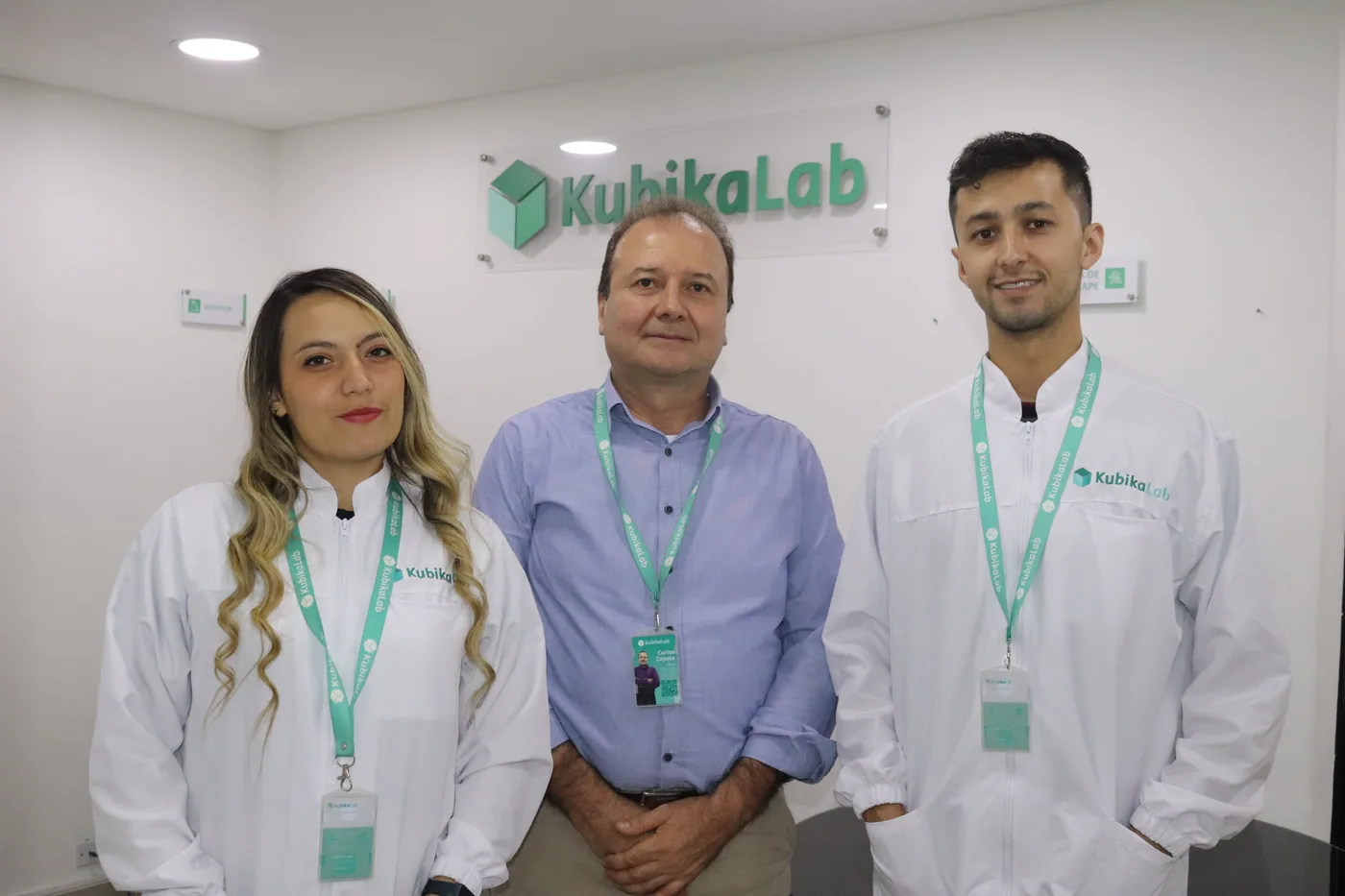 Tres integrantes del equipo de KubikaLab frente a la marca del laboratorio.
