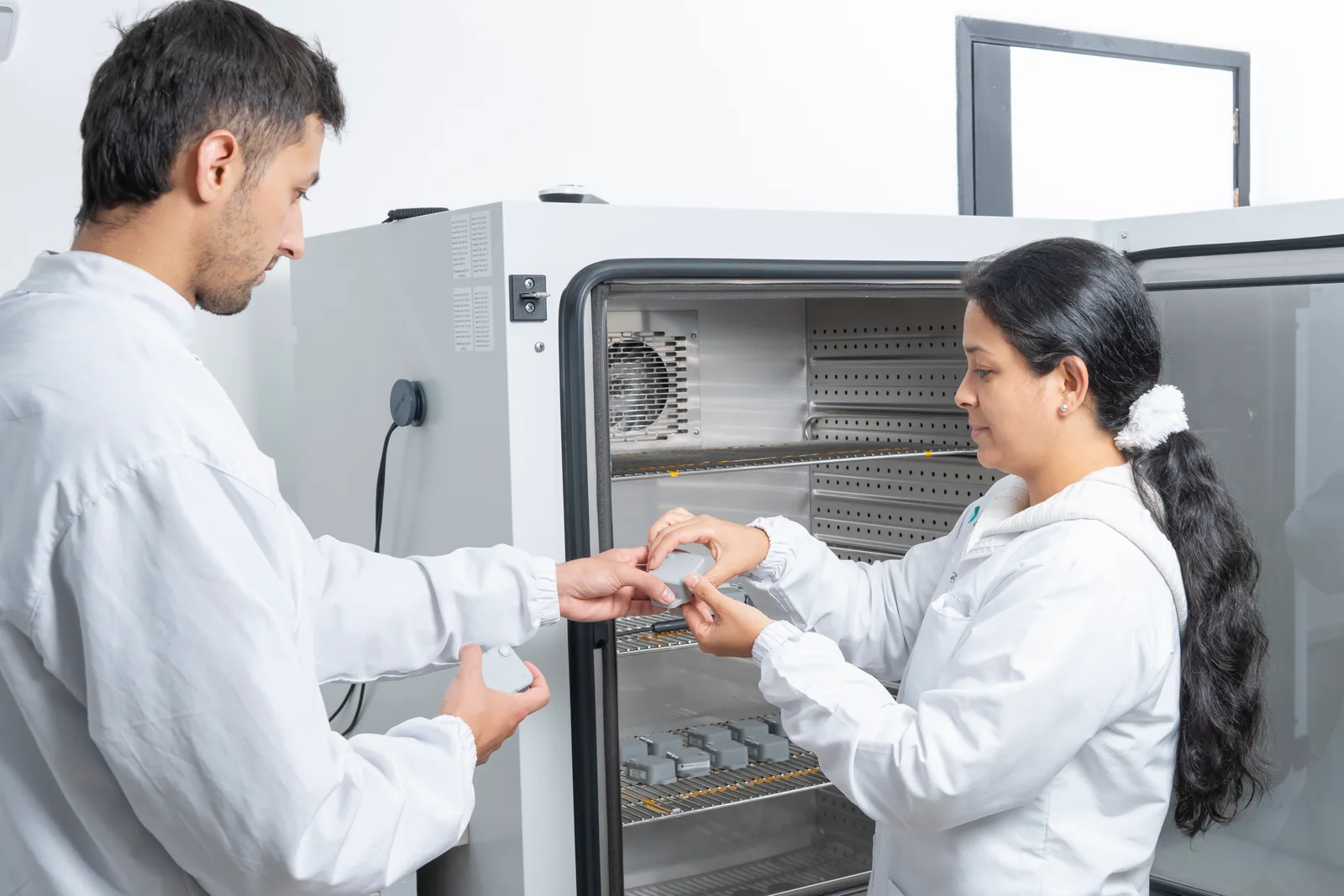 Dos especialistas de KubikaLab preparando sensores junto a una cámara del laboratorio.